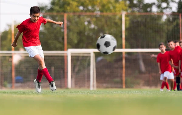 Menino chutando futebol no campo de esportes — Fotografia de Stock