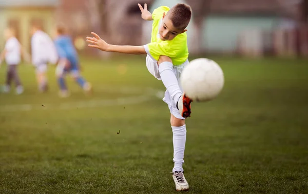 Pojken sparkar fotboll på idrottsplatsen — Stockfoto