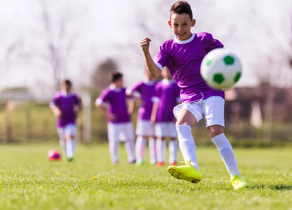 Pojken sparkar fotboll på idrottsplatsen — Stockfoto