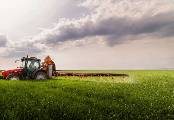 Traktor som sprutar bekämpningsmedel på vetefält med spruta på kronan — Stockfoto