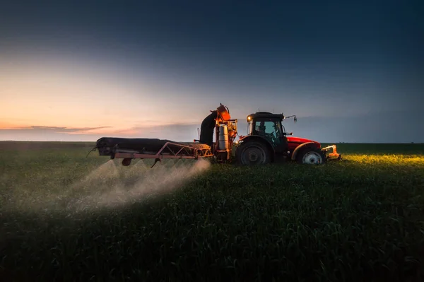 Trattore che spruzza pesticidi sul campo di grano con spruzzatore al sole — Foto Stock