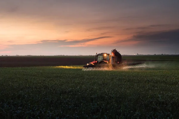 Trekker sproeien van pesticiden op tarweveld met sproeier op sunse — Stockfoto