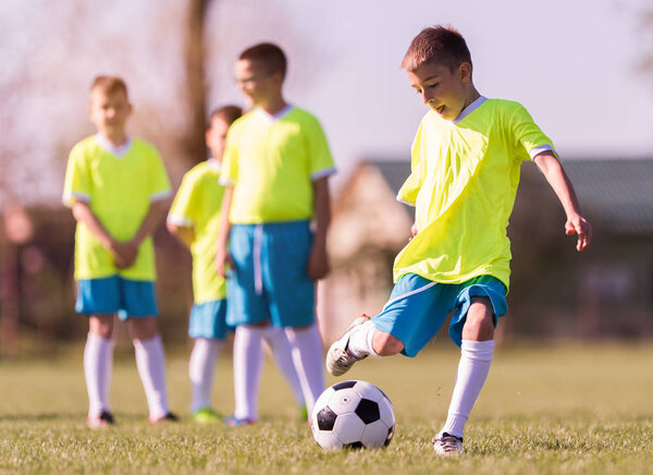 Мальчик пинает футбол на спортивном поле
