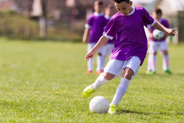 Chico pateando fútbol en el campo de deportes — Foto de Stock