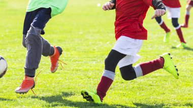 Çocuklar sahada futbol oynuyor.