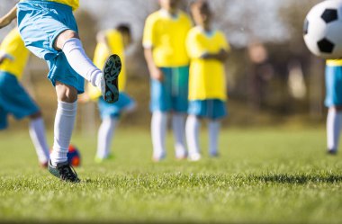 Çocuklar sahada futbol oynuyor.