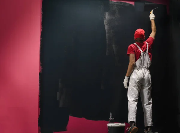 壁に絵を描く男 黒い色の赤全体的な絵画の壁の画家 — ストック写真