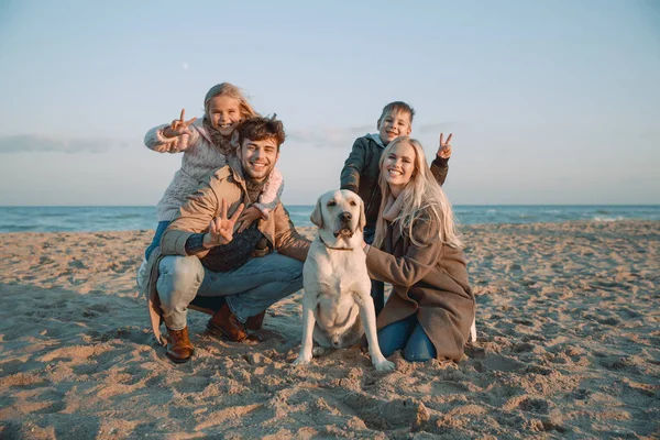 Family with dog showing peace symbols