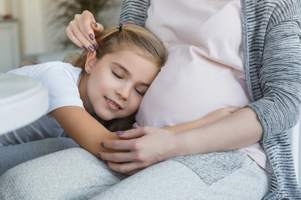 欢快的女儿在怀孕的母亲肚子上睡觉的裁剪图像 — 图库照片