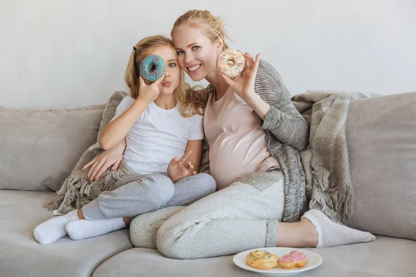 幸せな妊娠中の母親と娘のドーナツを楽しんで  — 無料ストックフォト