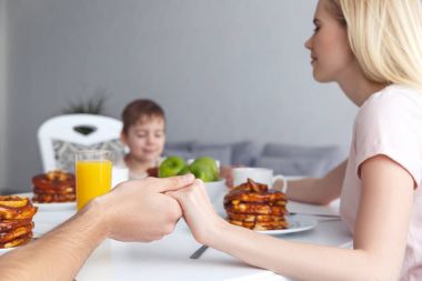 Kahvaltıdan önce dua genç Aile fotoğrafını kırpılmış
