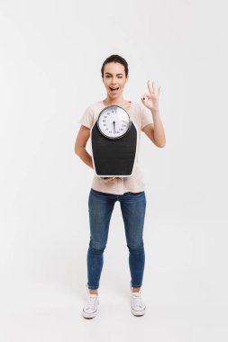 ölçekler tutarak ve iyi işaret üzerine beyaz izole gösteren genç kadın