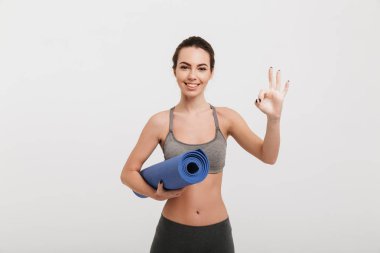yoga mat beyaz izole iyi işaret gösteren genç kadınla