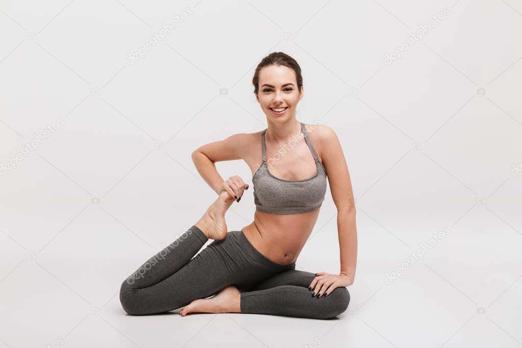 young sportswoman stretching legs isolated on white