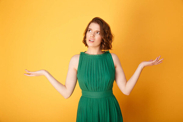 portrait of confused woman with outstretched arms isolated on orange