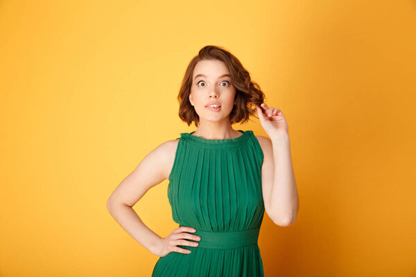 portrait of young surprised woman akimbo isolated on orange