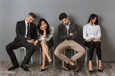 resmi yorgun Interracial iş adamları iş görüşmesi için beklerken sandalyelere uyku giymek