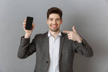 boş ekran ile akıllı telefon elinde gri duvar arka planı gösteren gülümseyen işadamı portresi