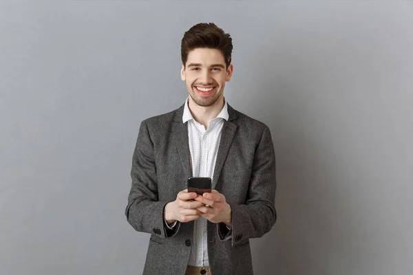 Retrato Empresário Sorridente Com Smartphone Contra Fundo Parede Cinza — Fotografia de Stock