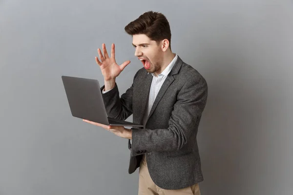 Empresário Frustrado Terno Com Laptop Contra Fundo Parede Cinza — Fotografia de Stock