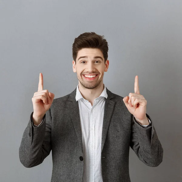 Retrato Homem Negócios Sorridente Terno Apontando Para Parede Cinza — Fotografia de Stock