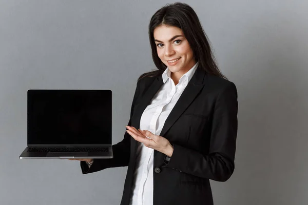 Smiling Businesswoman Pointing Laptop Blank Screen Grey Wall Background — Stock Photo, Image