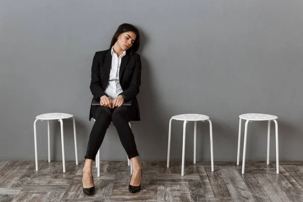 stock image tired businesswoman in suit with laptop sleeping on chair while waiting for job interview