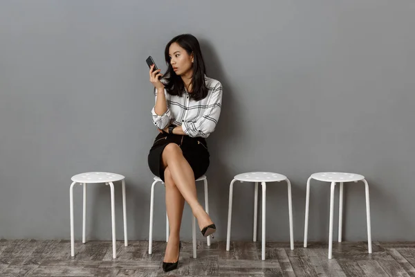 Ασιατικές Επιχειρηματίας Ψάχνει Στο Smartphone Στο Χέρι Κατά Την Αναμονή — Δωρεάν Φωτογραφία