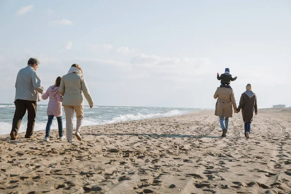 Familia multigeneracional caminando en la orilla del mar - foto de stock