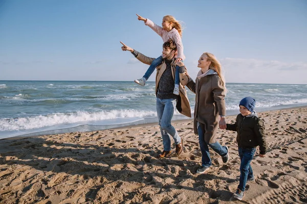 Familia caminando en la orilla del mar en otoño - foto de stock