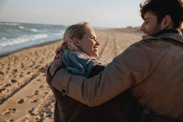 Sonriente pareja abrazándose en la orilla del mar - foto de stock