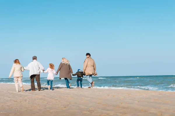 Familia caminando en la orilla del mar - foto de stock
