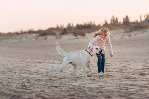 Child running with dog on beach — Stock Photo