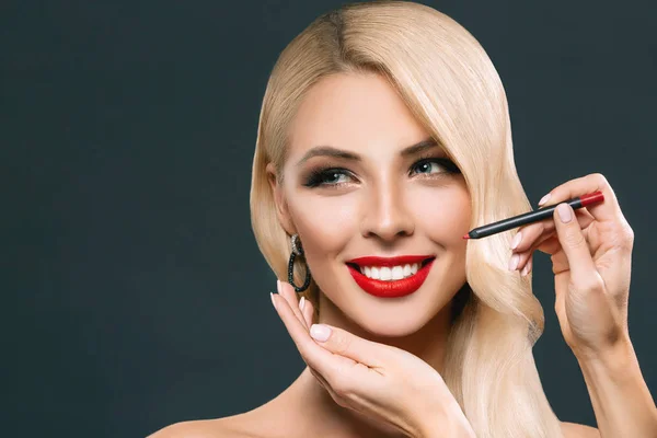 Beautiful smiling woman making red lips with cosmetic pencil, isolated on grey — Stock Photo