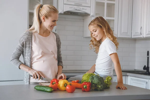 Sorrindo mãe grávida e filha cozinhar juntos — Fotografia de Stock