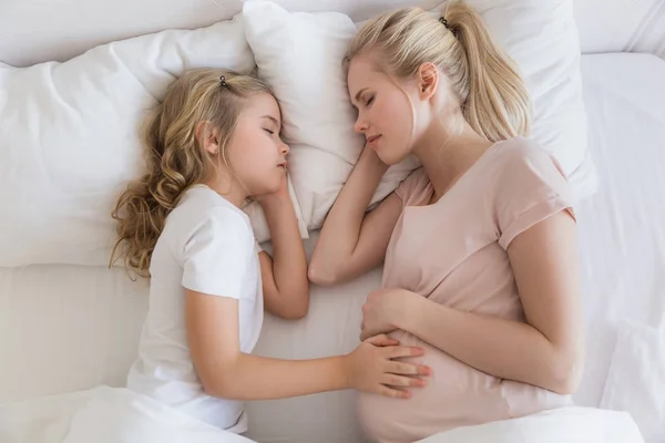 Vista superior de la hija y la madre durmiendo en la cama - foto de stock