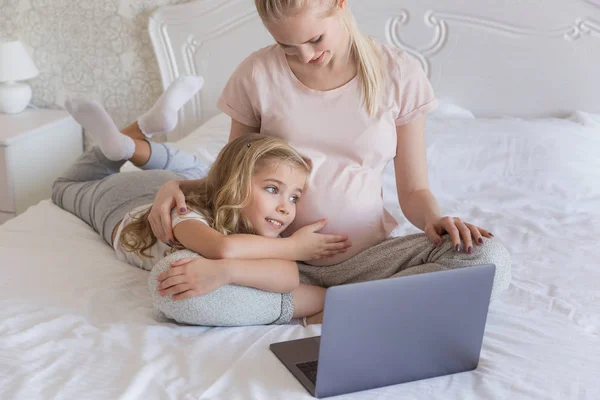 Daughter touching pregnant mother belly on bed — Stock Photo