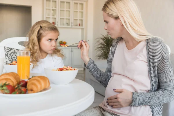 Hija rechazando comida de madres embarazadas en la cocina - foto de stock