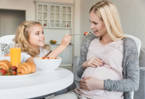 Fille souriante nourrissant mère enceinte — Photo de stock