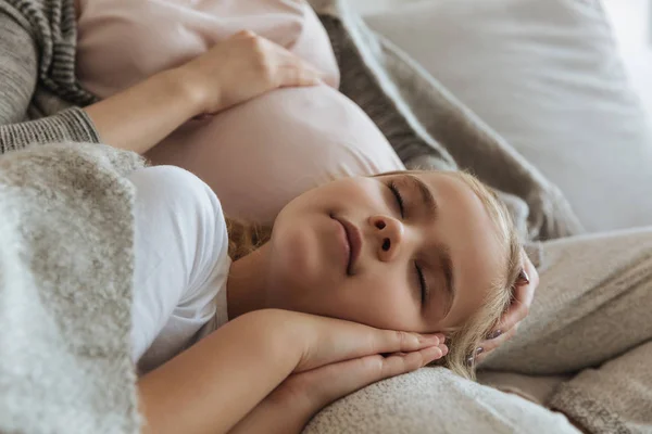 Abgeschnittenes Bild der Tochter, die auf den Beinen der schwangeren Mutter schläft — Stockfoto