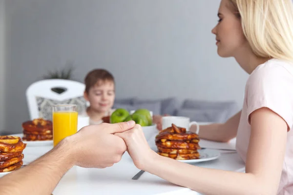 Обрізаний знімок молодої сім'ї, що молиться перед сніданком — стокове фото