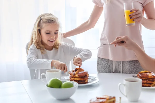 Hija feliz desayunando con sus padres - foto de stock