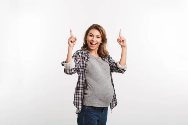 Portrait of happy pregnant woman pointing up isolated on grey — Stock Photo