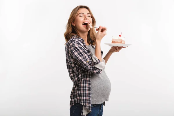 Happy young pregnant woman eating cake isolated on white — Stock Photo