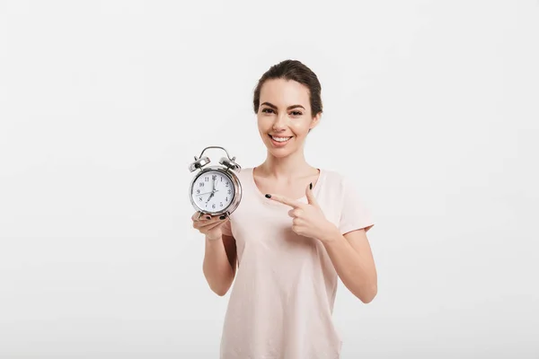 Fille souriante pointant sur réveil isolé sur blanc — Photo de stock