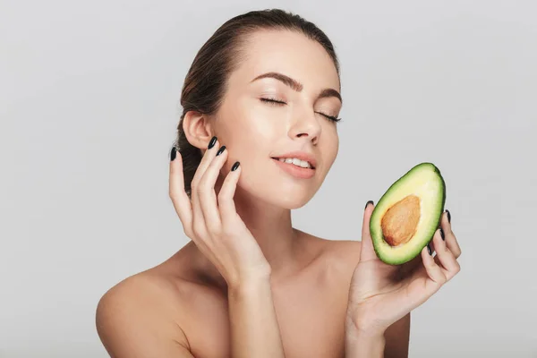 Junge Frau mit perfekter Haut, die die Hälfte der frischen Avocado auf weiß isoliert hält — Stockfoto