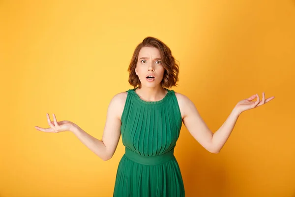 Portrait of young shocked woman with outstretched arms isolated on orange — Stock Photo