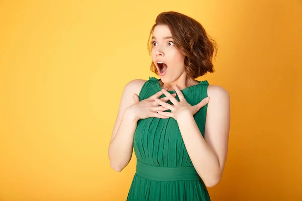 Retrato de mujer joven sorprendida mirando hacia otro lado aislado en naranja - foto de stock