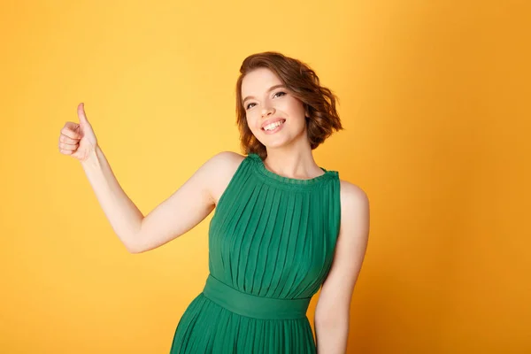 Portrait of pretty smiling woman showing thumb up isolated on orange — Stock Photo