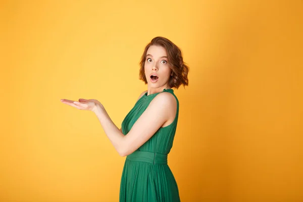 Side view of shocked woman with outstretched arms looking at camera isolated on orange — Stock Photo